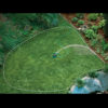 A neatly manicured garden with a vibrant green lawn, a garden hose, decorative plants, and a small pond is visible in this overhead image.