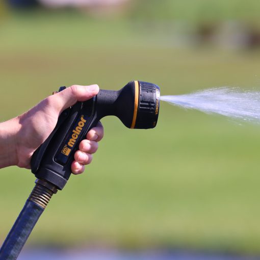 Melnor XT Metal 7-Pattern Nozzle spraying the full spray pattern in front of green background