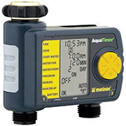 A digital irrigation timer with a yellow dial and a large LCD screen showing time and settings. It has inlet and outlet hose connectors.