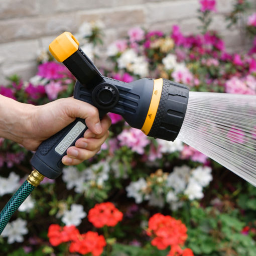 Melnor Torrent Hose Nozzle watering with the shower spray setting in front of colorful flowers