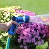 A person's hand is holding a blue garden hose nozzle labeled 