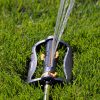 Melnor Turbo Oscillating Sprinkler spraying water over lush lawn. View from the side