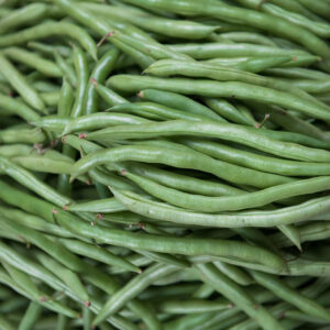 The image shows a pile of fresh green beans with a vibrant green color, closely packed together, showcasing their long, slender shapes and natural texture.