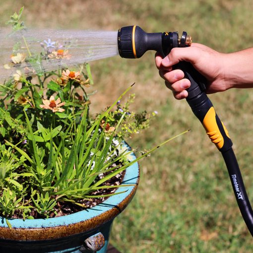 Melnor XT Fusion garden hose connected to a Melnor hose nozzle spraying potted flowers